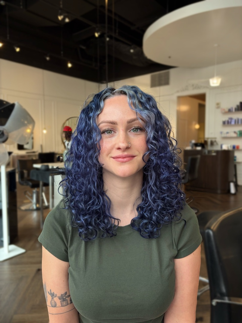 A client at Moe's Beauty Co. with hand-painted blue curls after a curl-by-curl cut and color